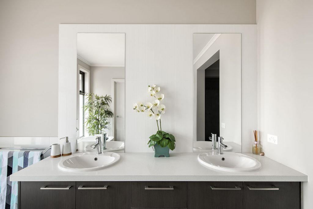 Modern bathroom featuring his and her sinks, sleek black wood cabinets, side-by-side mirrors, and elegant quartz countertops for a sophisticated, balanced design.